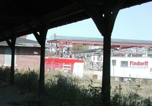 New steel canopies for buses, framed in this view by aged steel pillars supporting train platform canopies
