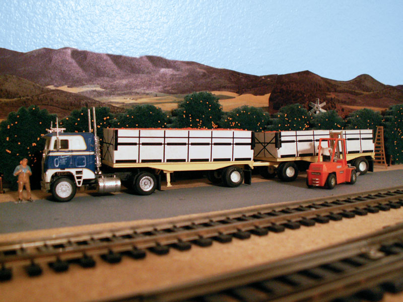 A forklift loading the ag bins full of oranges onto a truck trailer