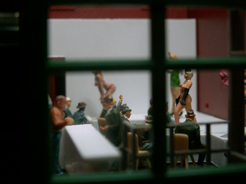 The girl wearing only a top hat and gloves is on center stage